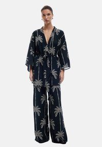 Czarny zestaw kimono i spodni o szerokich nogawkach z białym haftem palm. Posiada głęboki dekolt w kształcie litery V i materiałowy pasek. Miękka tekstura i luźny krój.