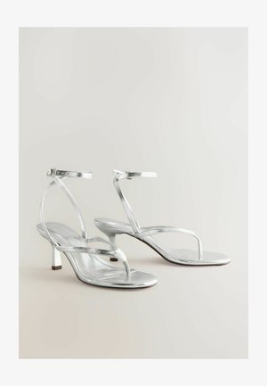 Stříbrné metalické sandály na podpatku mají minimalistický design s tenkými pásky a štíhlým blokovým podpatkem. Hladký materiál, otevřená špička.