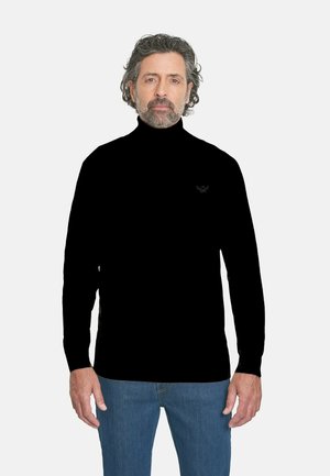 Suéter negro de cuello alto en tejido de punto suave, diseño ajustado, con un logo sutil en el pecho. Combinado con jeans de mezclilla azules.