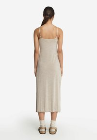 Beżowa, bezrękawnikowa sukienka o długości midi, z cienkimi ramiączkami i prostym krojem. Posiada boczne rozcięcie i jest wykonana z miękkiej, teksturowanej tkaniny.