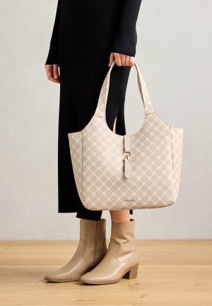 Beige patterned tote bag with a smooth texture, curved handles, and a detachable accent. Paired with beige ankle boots and a black ribbed dress.