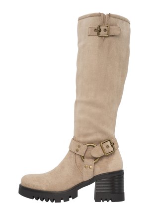 Botte en suède beige hauteur genou avec un épais talon noir, des accents de boucle et une semelle texturée. Courbure soudaine en haut pour le design.