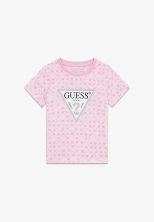 Világos rózsaszín pamut póló geometriai mintával. Triangularis ezüst logócímkével, amelyen vastag fekete betűkkel a "GUESS U.S.A." felirat olvasható. Kerek nyakkivágás.