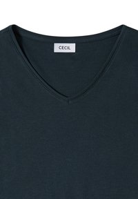 Chemise vert foncé à col en V avec une étiquette blanche indiquant "CECIL" cousue à l'intérieur du col arrière.