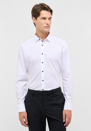 Witte lange mouw shirt met een gestructureerde kraag, featuring zwarte knopen en een gladde textuur, gecombineerd met donkere broeken.
