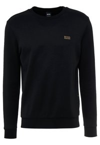 Svart sweatshirt med långa ärmar, rundad halsringning och ribbade ärmslut. Har en liten guldfärgad logotyp på bröstet och en texturerad tyg.