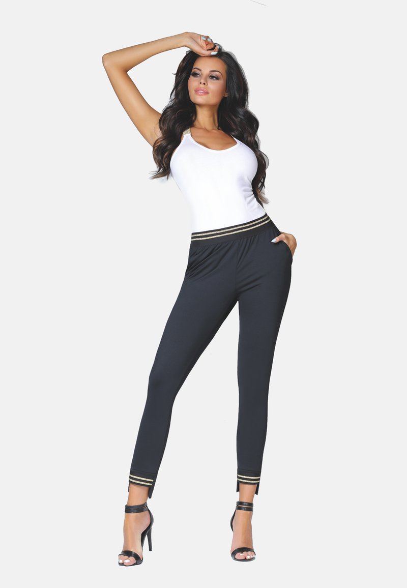 Czarne legginsy z złotymi paskami akcentującymi w talii i na mankietach, zestawione z dopasowanym białym topem na ramiączkach. Materiał wydaje się gładki i elastyczny.