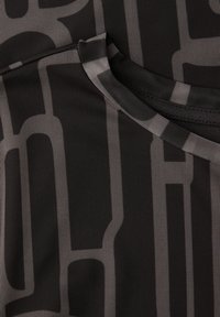 Czarna tkanina z geometrycznym wzorem w kolorze szarym. Okrągły dekolt i teksturowana powierzchnia, prezentujące oddychający i lekki design.