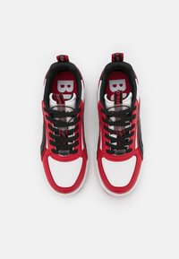 Red and white sneakers with black accents, featuring a textured upper, black laces, a padded collar, and a clearly labeled insole design.