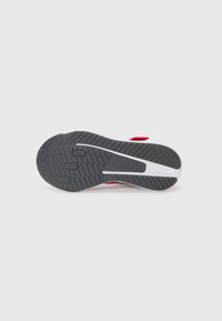 Red athletic shoe sole in black with white accents, featuring tread patterns for grip and support, lightweight materials, and a curved design.