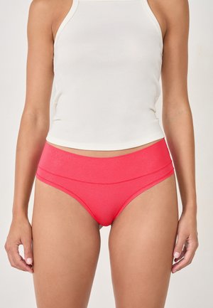 Mutandine alte in vita di colore rosa con una texture liscia e lucida e un design a doppio pannello, abbinate a un top in cotone bianco a coste attillato.
