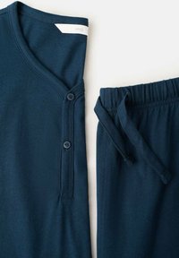 Conjunto de ropa cómoda en azul marino que incluye un top de manga corta con escote en V y detalles de botones, combinado con pantalones de cintura elástica y cordón ajustable.