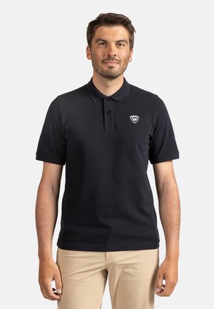 Polo noir avec un col classique, trois boutons et un logo sur la poitrine gauche ; fabriqué en tissu lisse avec des manches courtes.