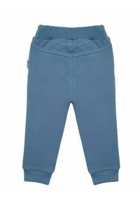 Niebieskie bawełniane spodnie dresowe z elastycznym paskiem w talii, prążkowanymi mankietami i gładką fakturą. Z boku znajduje się mała metka.