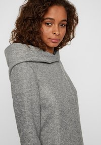 Felpa grigia con cappuccio, caratterizzata da un motivo a maglia testurizzato, dal taglio ampio e con un collo largo e ripiegato. Design casual senza hardware visibile.