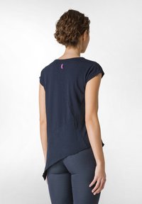 Top bleu marin cu mânecă scurtă, cu un design geometric, având o margine curbată și o etichetă mică violet pe spate. Textură de țesătură netedă și moale.