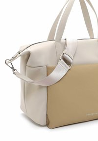Bolso tote beige y crema hecho de material sintético. Presenta asas cortas y una correa ajustable y desmontable. Cierre de cremallera y acentos laterales.