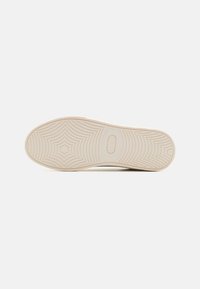 Kreemivärviline sneakerite talla osa, millel on tekstureeritud muster, kus on kontsentrilised ringid ja keskel tähtkujuline disain. Vastupidav kummimaterjal.