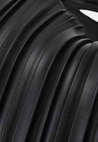 Sort læder med en ribbet tekstur, der har vekslende glatte og teksturerede riller, som fremhæver et struktureret og moderne design.