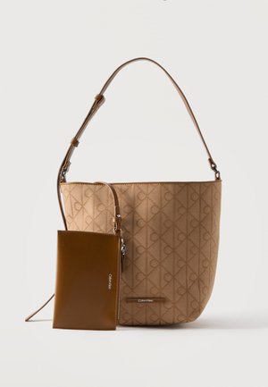 Sac seau beige Tan de Calvin Klein avec motif de logo embossé, bandoulière réglable et petite pochette zippée marron attachée.
