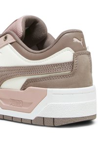 Puma sneakers med en övervägande krämfärgad ovandel och ljusbruna accenter, mjuka mocka- och mesh-texturer, samt en kraftig vit sula.