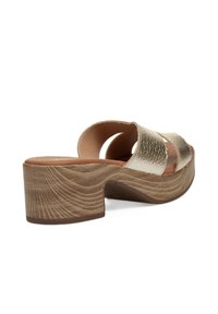 Sandal de textura dorada con dos amplias correas cruzadas. Presenta una plataforma de tacón con patrón de madera en color marrón claro y una plantilla lisa en tono marrón claro.