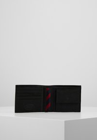 Schwarze Lederbörse mit mehreren Kartenfächern, einem Fach für Geldscheine und einem gemusterten Innenfutter mit roten und blauen Streifen.