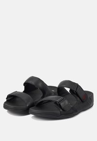 Zwarte sandalen met een ontwerp van twee banden van textuurleer. Verstelbare banden met een rode accent, gewatteerde voetbed en flexibele zool.