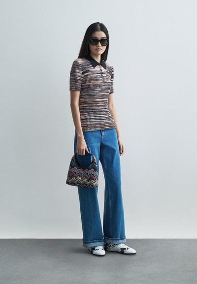 Πόλο μπλουζάκι πλεκτό με πολύχρωμες ρίγες, μαύρο γιακά, φαρδιές μπλε τζιν παντελόνες, τσάντα με σχέδιο ζιγκ-ζαγκ και μαύρα υπερμεγέθη γυαλιά ηλίου.