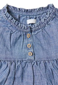 Blauwe denim jurk met ruches bij de halslijn, drie houten knopen aan de voorkant en een geplooide rok. Zachte stof met een gestructureerde afwerking.