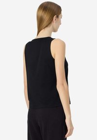 Top senza maniche nero con scollo rotondo e vestibilità morbida. Realizzato in un tessuto morbido e liscio, con cuciture minime per un design pulito.