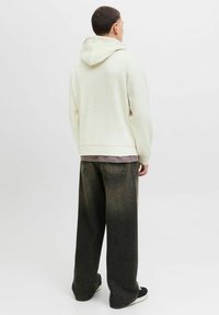Felpa con cappuccio di colore crema chiaro, dalla vestibilità comoda, in tessuto strutturato e con polsini a coste, abbinata a jeans in denim scuro a vestibilità ampia.