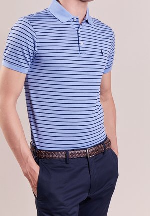 Hellblaues Polohemd mit kurzen Ärmeln und marineblauen Streifen, ausgestattet mit einem Polo-Kragen und einem kleinen Logo. Tragen mit dunklen marineblauen Hosen und einem geflochtenen braunen Gürtel.
