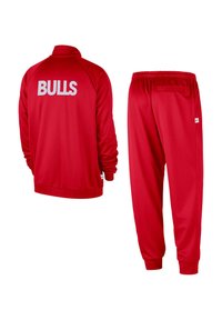 Punainen urheiluasu, jossa on vetoketjullinen takki, jossa lukee "BULLS" valkoisella selässä, sekä yhteen sovitetut kapenevat housut, joissa on elastinen vyötärö.