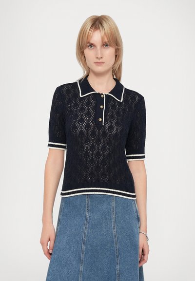 Polo shirt in pizzo di colore blu navy con colletto, maniche corte, bottoni dorati e rifiniture bianche lungo il colletto e le maniche.
