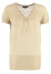 Kortärmad beige topp med snörning i V-ringning, stickad textur och ribbad nederkant. Har metalliska detaljer vid snörningsöppningarna för extra detaljer.