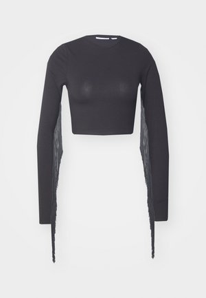 Czarny top typu crop z długimi rękawami, z frędzlami po jednej stronie, wykonany z gładkiego, elastycznego materiału.