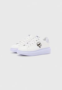 Witte sneakers van glanzend leer, ronde neus en dikke paarse zool. Bevat veters en een grafische logo-accent aan de zijkant.