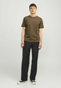 Brown cotton t-shirt with short sleeves paired with black pleated trousers and black canvas sneakers. Simple design, relaxed fit.