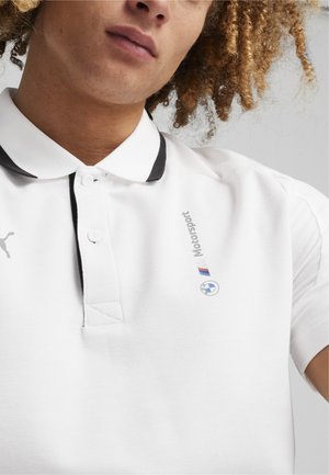 Biała koszulka polo z czarnym kołnierzykiem, z guzikami i haftowanym napisem "Motorsport" oraz emblematem BMW.