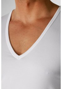 Weißes Baumwoll-T-Shirt mit V-Ausschnitt und taillierter Passform. Auffällige glatte Textur und ein flacher Ausschnitt, der die Haut darunter betont.