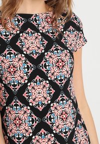 Robe noire à manches courtes avec un motif floral multicolore dans des tons de rose, bleu et blanc, dotée d'un col rond et d'une coupe décontractée.