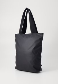Black tote bag made of textured fabric with flat, wide straps. Rectangular shape with a smooth surface and subtle grid pattern.