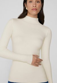 Korte mouwen crèmekleurige coltrui gemaakt van een soepele, rekbare stof, met een aansluitende pasvorm en duimgaten voor een elegante uitstraling.