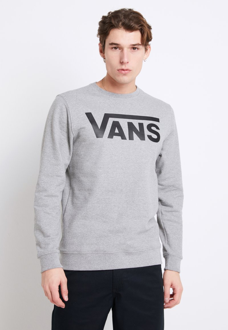 Sudadera gris de manga larga, con un destacado logo negro de "VANS" en el pecho. Puños y bajo acanalados. Textura suave.