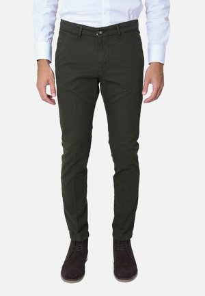 Chino in cotone verde scuro con una vestibilità slim, con chiusura a bottone e tasche laterali, abbinati a stivali in suede marrone.