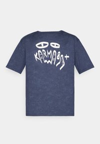 T-shirt in cotone blu navy con un design grafico che presenta occhi bianchi e la parola "KARMA" in un font giocoso sulla schiena. Maniche corte, vestibilità rilassata.