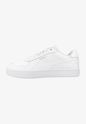 Zapatillas de tenis blancas hechas de material sintético con puntera perforada, cordones planos y sutil logo de Puma en color plateado. Presenta una suela de goma gruesa.