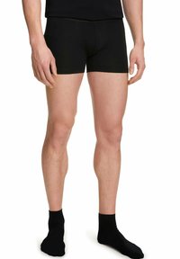 Czarne bawełniane bokserki o dopasowanym kroju, z elastycznym pasem i gładką teksturą. Noszone z czarnymi skarpetami.