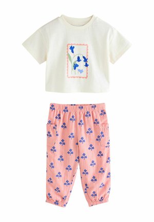 Zweiteiliges Outfit aus Baumwolle mit einem cremefarbenen Kurzarmoberteil mit Blumenmuster und rosafarbenen Hosen mit blauen Blumenmustern und Taschen.